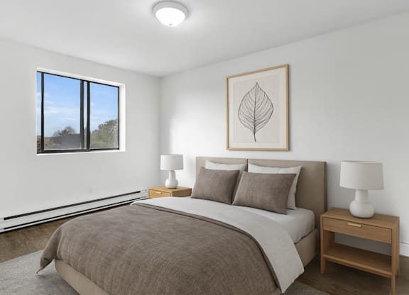 A bedroom with a large bed and a framed leaf picture on the wall.