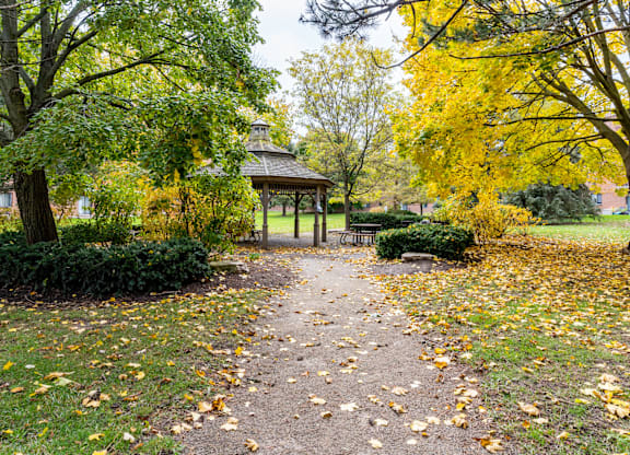 A gazebo sits in the middle of a park with a path leading to it.
