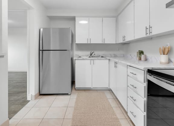 A modern kitchen with white cabinets and a stainless steel refrigerator.