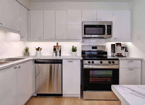 A modern kitchen with white cabinets and stainless steel appliances.