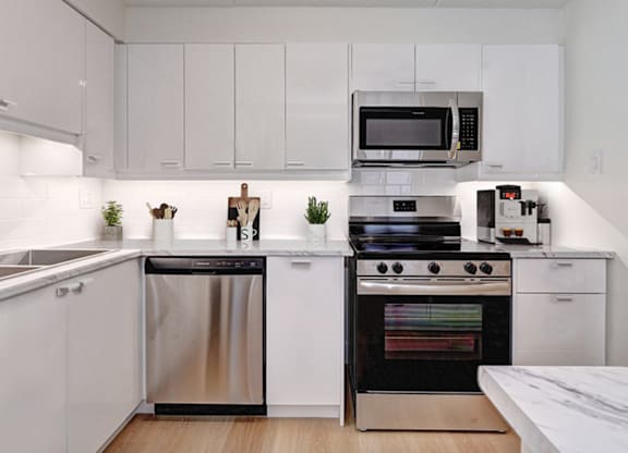 A modern kitchen with white cabinets and stainless steel appliances.