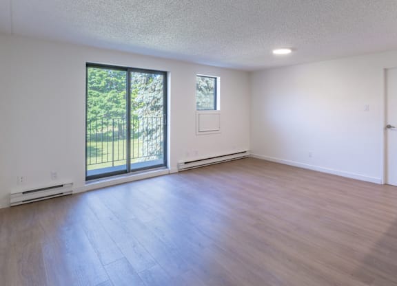 A room with a sliding glass door and wood flooring.
