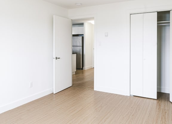 A white door is open in a room with wood flooring.