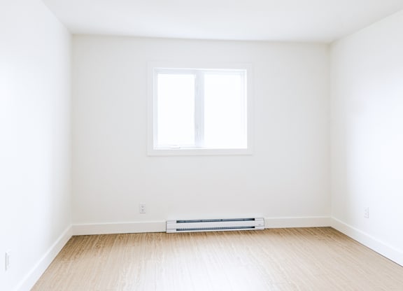 A room with a window and a radiator on the floor.