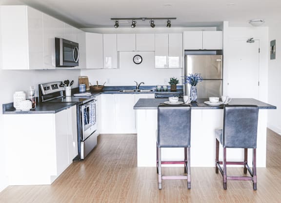 A kitchen with a black countertop and white cabinets.