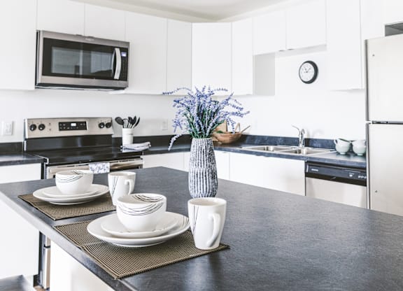 A kitchen with a black countertop and white cabinets.