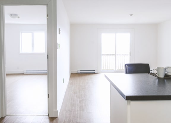 A black countertop with a white fridge and a black chair in the middle of the room.