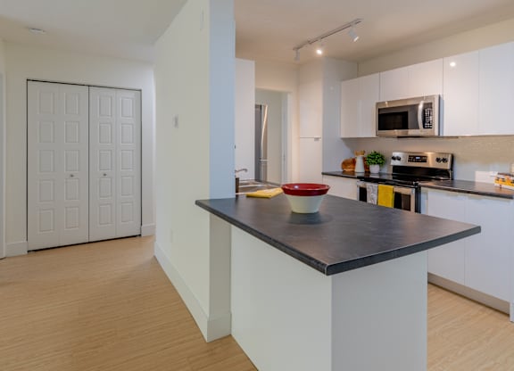 A kitchen with a black countertop and white cabinets.