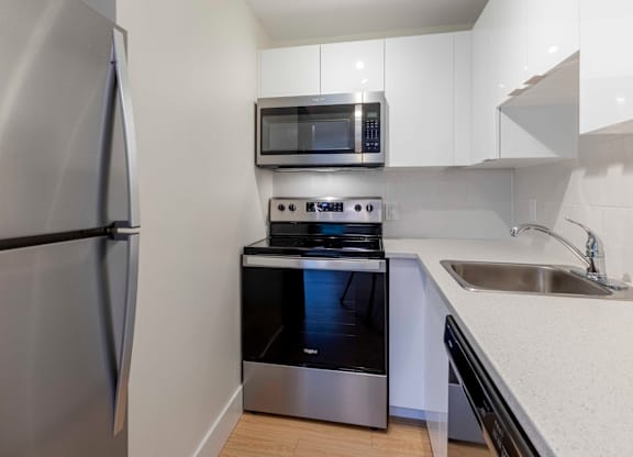 A kitchen with a stainless steel refrigerator, microwave, oven, and sink.