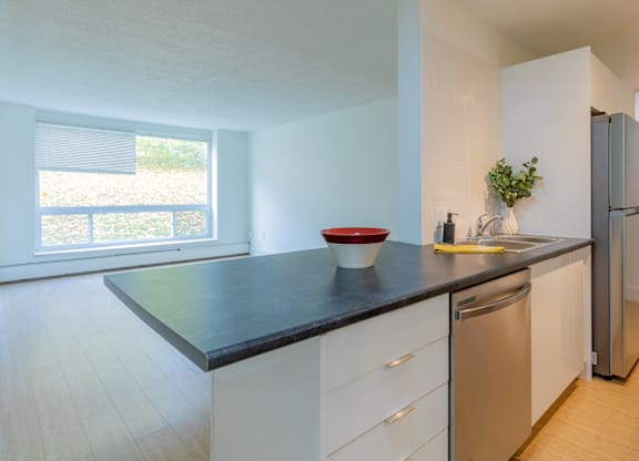 A kitchen with a black countertop and white cabinets.