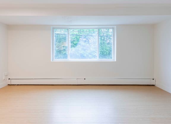 A room with a large window and wooden flooring.