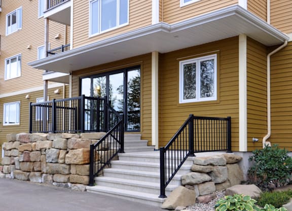 A brown house with a black railing on the stairs.