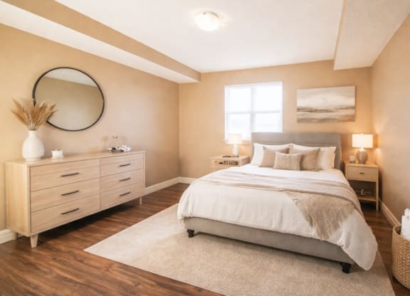 A bedroom with a large bed, a dresser, and a mirror on the wall.