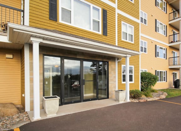 A yellow building with a glass door and a white pillar.