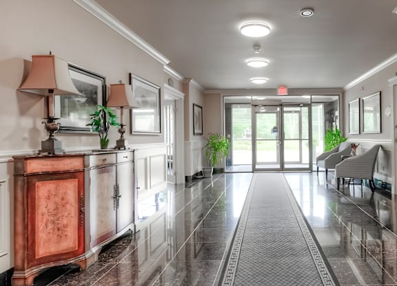 A hallway with a marble floor and a red cabinet.