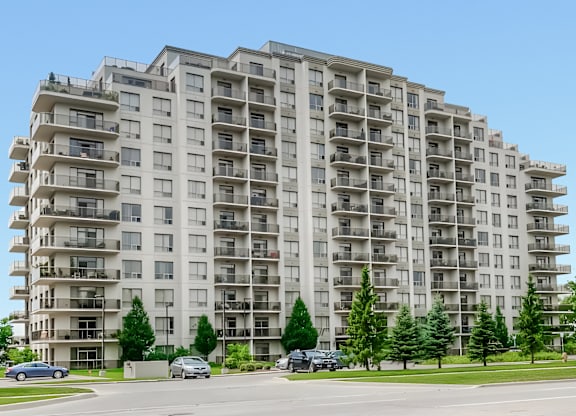 A large apartment building with balconies and trees in front.