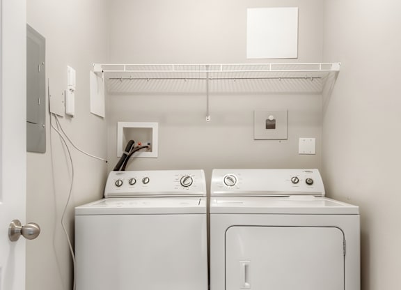 Two white washing machines in a small laundry room.