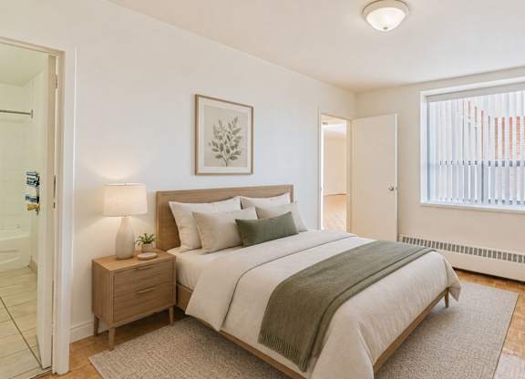 A bedroom with a bed, nightstand, and lamp.