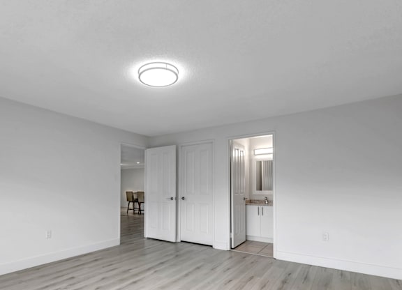 A white room with a light on the ceiling and a wooden floor.