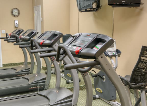 A gym with treadmills and a television mounted on the wall.