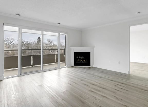 A large, empty room with a fireplace and sliding glass doors.