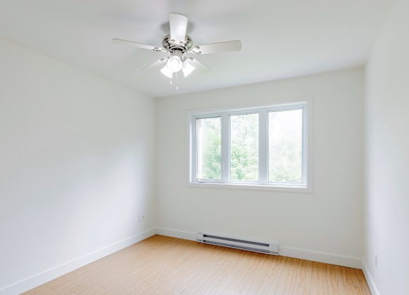 A room with a ceiling fan and a window.