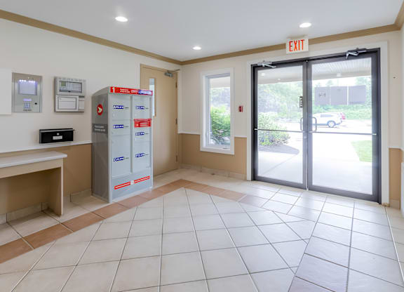 A white tiled lobby with a red exit sign.