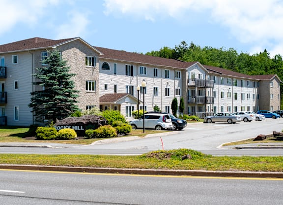 A large apartment complex with a parking lot in front.