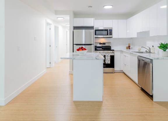 A modern kitchen with white cabinets and stainless steel appliances.