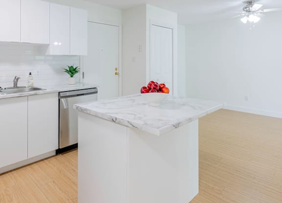 A kitchen with white cabinets and a marble island.