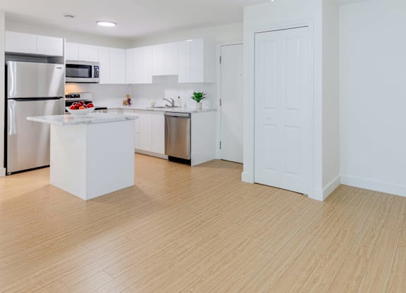 A kitchen with white cabinets and a wooden floor.
