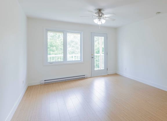 A room with a ceiling fan and a window with a view of trees.
