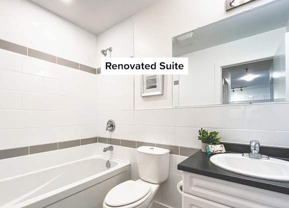 A renovated bathroom suite with a white toilet, sink, and bathtub.