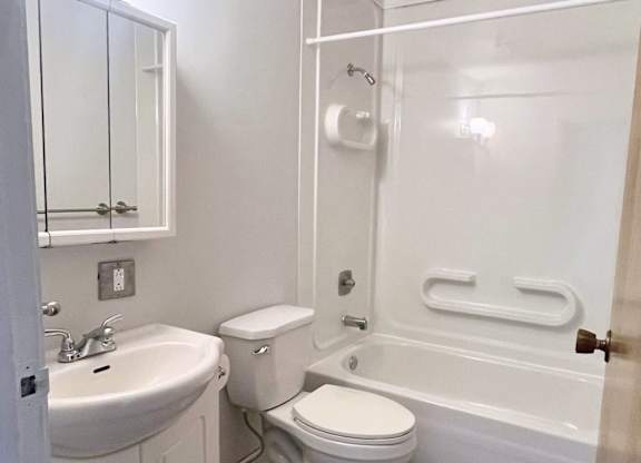 A white bathroom with a toilet, sink, and bathtub.