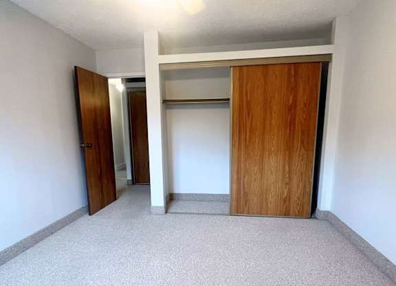 A room with a carpeted floor and two wooden doors.