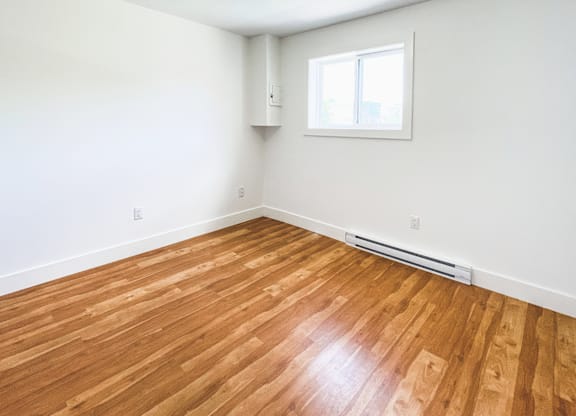 A room with wooden flooring and a window.