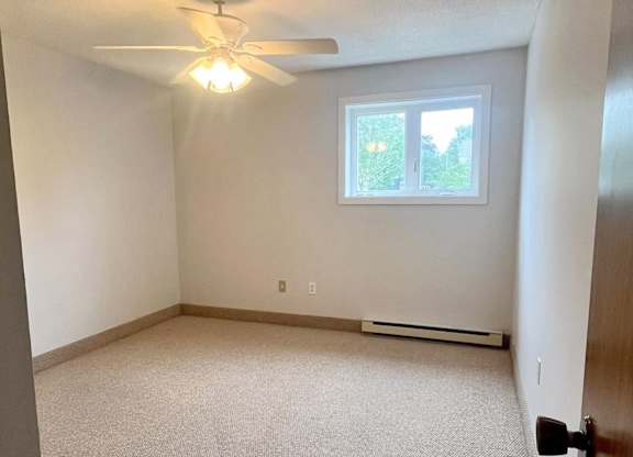 A room with a ceiling fan and a window.