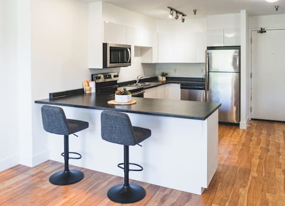 A kitchen with a black countertop and two bar stools.
