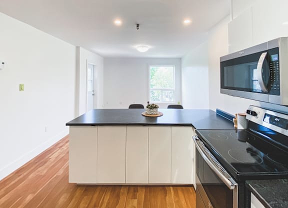 A kitchen with white cabinets and black countertops.