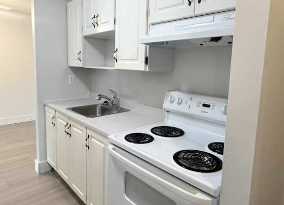 A white kitchen with a stove and sink.