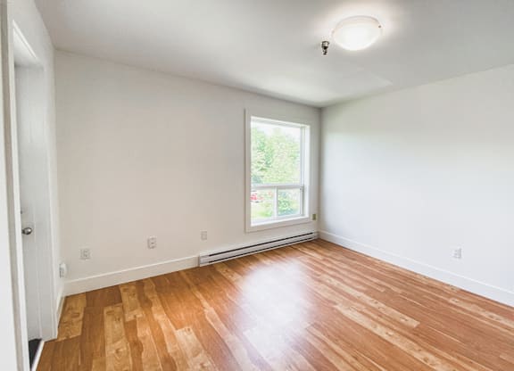 A room with wooden flooring and a window.