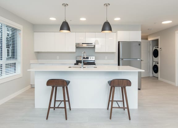 A modern kitchen with white cabinets and a large island with two stools.