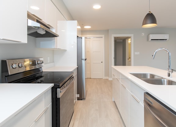 A modern kitchen with white cabinets and stainless steel appliances.