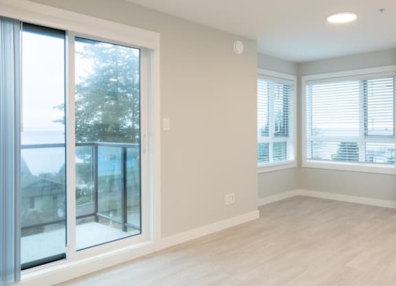 A room with a sliding glass door and a window with blinds.
