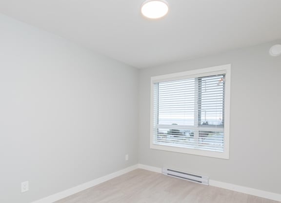 A room with a window and a wooden floor.