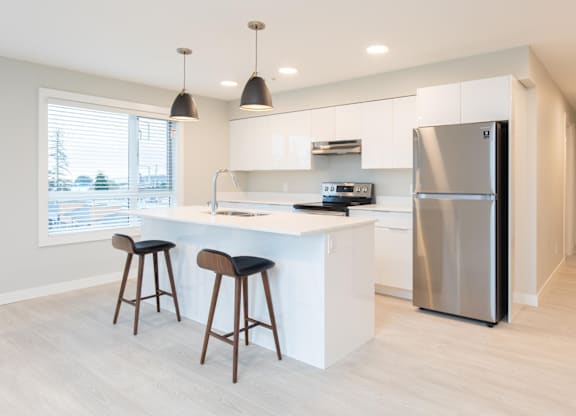 A modern kitchen with a white countertop and a stainless steel refrigerator.