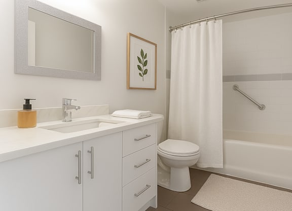 A white bathroom with a toilet, sink, and shower.