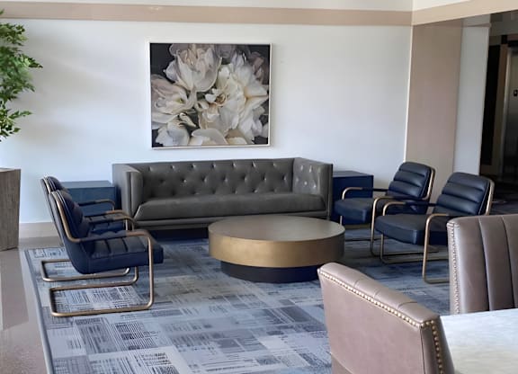 A grey sofa with a gold coffee table in front of a grey and blue carpet.