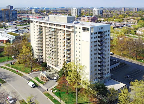 A large white apartment building with a parking lot in front.