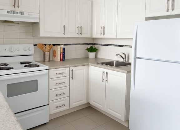 A white kitchen with a stove, sink, and refrigerator.